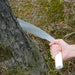 Kakuri Temagari Large Hand Pruning Saw with wooden handle and metal blade with crosscut teeth being used to cut into a log outside